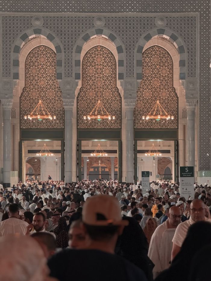 A large gathering of people inside Al-Masjid al-Haram in Makkah, Saudi Arabia showcasing Islamic architecture.