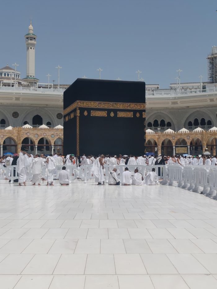 Pilgrims in traditional attire perform rituals around the Kaaba in Mecca, Saudi Arabia.